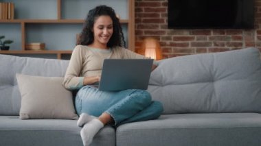 Relaxed freelancer woman SMM specialist web programmer housewife student businesswoman girl woman sitting on couch at home typing laptop working remote distant job quarantine using wireless computer