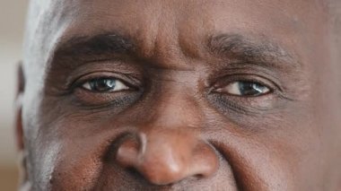 Ön tarafı kapatın. Cildinde kırışıklıklar olan erkeklerin yüzünün yarısı iyi göremeyen kameraya bakıyor. Afro-Afrikalı tanınmaz halde.