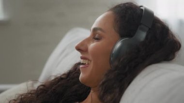 Kıvırcık saçlı, gülümseyen kadın. Yorgun, sakin bayan. Rahat koltukta dinleniyor.