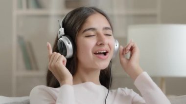 Rahatlamış, kulaklıklı güzel bir genç kız favori müzik dansını dinliyor ritmik müzikal soundtrack mp3 müzik listesinin tadını çıkarıyor enerjik yüksek sesli melodi eğlenceli ruh hali aktif ev partileri