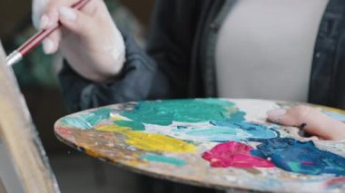 Kapanış kadın el sanatları ressamı resim çizerken, atölye dersinde resim yaparken yağlı boya paletini kullanarak resim çizmenin zevkini çıkartıyor.