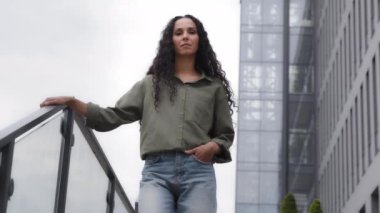 Kıvırcık saçlı, uzun saçlı kadın avukat bayan iş kadını ofis binasının merdivenlerinde poz veren şehir merkezindeki merdivenlerde kameraya gülümseyen kadın.