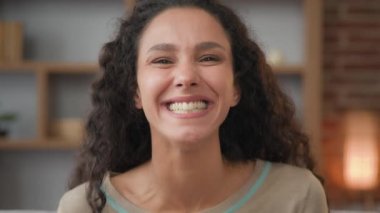 Kapalı alanda çekilmiş portre mutlu kadın yüzü neşeli kıvırcık saçlı İspanyol kadın mutlu ruh hali espri üzerine kahkaha komik komedi diş tebessümüyle gülen eğlenceli anlar.