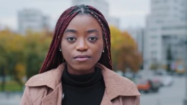 Kadın portresi. Yakın plan. Ciddi, güzel, düşünceli, şık, afro-amerikalı kadın. Dışarıda durmuş kameraya bakıyor.