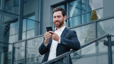 Gülümseyen adam elinde cep telefonuyla sosyal ağlara göz atıyor mutlu düşünceli iş adamı rüyaların müşteriyle ya da arkadaşıyla telefonda mesajlaştığını düşünüyor.