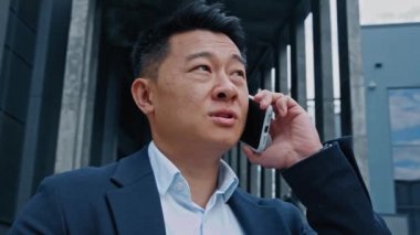 Asya Koreli 40 'lı yaşlarında yetişkin bir lider yatırımcı, girişimci, şehir dışında cep telefonuyla konuşan bir pazarlamacı.