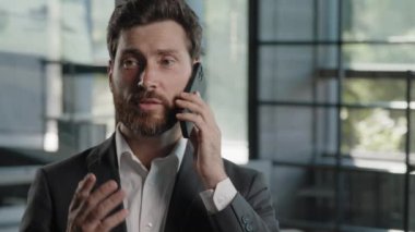 Beyaz sakallı, orta yaşlı iş adamı ofiste telefonla konuşuyor. Sanal satış görüşmelerini akıllı telefon konuşmalarıyla cep telefonu konuşmaları yaparak açıkla.