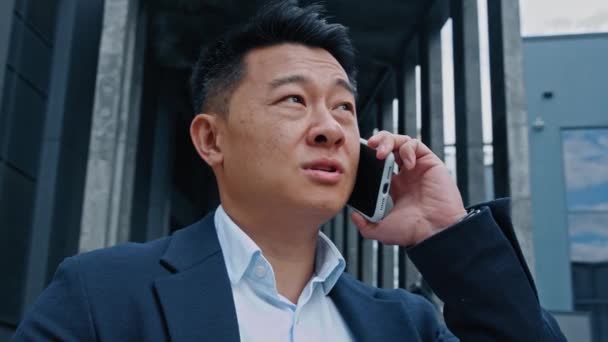 閉じるアジア系韓国人40代の大人のリーダー労働者投資家起業家ビジネスマン電話を屋外で話す営業マンは スマートフォンの呼び出しで遠くの携帯電話の話の答えの呼び出しを持っています — ストック動画
