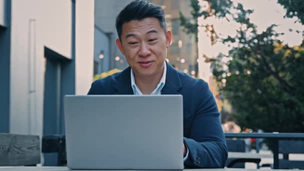 幸せな男性買い手アジアの大人40代の男性は屋外に座ってラップトップのWebカメラに新しい家の不動産からキーを示しています 中国の不動産業者のセールスマンの貿易電子商取引アパートオンラインで顧客とのオファーを議論 — ストック動画