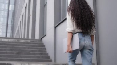 İş kadını, kadın, serbest çalışan kadın, profesyonel bayan, merdivenlerde yürüyen, ofis toplantısına giden, elinde bilgisayar laptopuyla şehir merkezine yakın bir yere gidiyor.