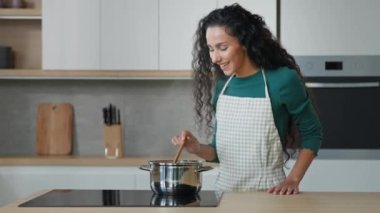 Güzel bayan aşçı ev hanımı, mutfakta aile için yemek pişiriyor sağlıklı diyet, aromatik kokulu sıcak yemek. Arap anne lezzetli çorba tarifi kullanır. Ev yapımı, doğal malzemelerle.