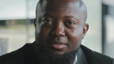 Gülümseyen Afro-Amerikan iş adamı şirket kurucusu kameraya bakıyor sakallı erkek ofis çalışanı başarılı girişimci yüzü ile ofiste yalnız poz veriyor yakın portre