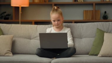 Sevimli küçük oyuncu kız öğrenci online modern bilgisayar oyunları oynuyor oyun seviyesinde sohbet mesajlarını dizüstü bilgisayarla evde tek başına çalışan medya içeriği karikatürlerini arıyor.