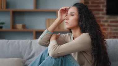 Endişeli üzgün endişeli endişeli İspanyol asıllı, beyaz kadın 30 'lu yaşlarda, kanepede oturan üzgün, stresli, kötü, istenmeyen, hamile, kapalı bir ortamda istenmeyen bir baş ağrısı.