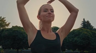 Beyaz tenli atletik kadın koşucu vücut ısısını arttırıyor spor kıyafetleri giyen koşucu kız sportif giysisi giyip, sabah nefes egzersizleri yapıyor sağlık hayatı için dışarıda.