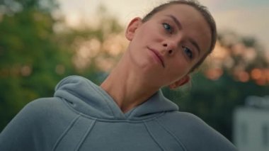 Beyaz, formalı, spor kıyafetli bir kadın, sabah sporu antrenmanlarına hazırlanmadan önce boynu yoğurur. Yoga dışarıda, yan yana eğilir. Vücut kaslarını kasmaktan kaçınır, profesyonel egzersiz yapar.