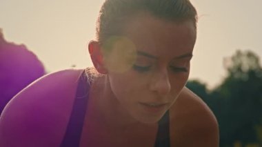 Motive olmuş genç kadın koşucu beyaz kadın koşucu başlangıç çizgisinde eğik pozisyonda oturur yarış maratonunu koşuya hazırlar koşuya hazırlanır gün doğumunda dışarıda spor antrenmanı hızı yapar