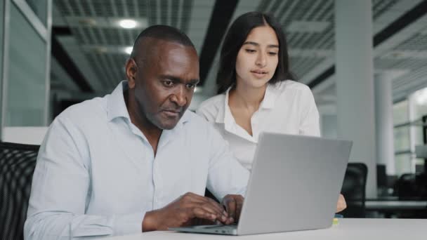 阿拉伯女领导导师帮助非洲男性同事在电脑工作中检查实习生在笔记本电脑上的错误 两名商界人士在办公室讨论团队合作中的公司项目软件 — 图库视频影像