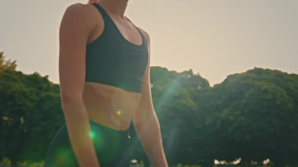 身穿黑色运动服的积极运动健美的金发女教练蹲在室外朝阳背景下运动健美训练泵臀部肌肉早操促进强壮健康的身体 — 图库视频影像