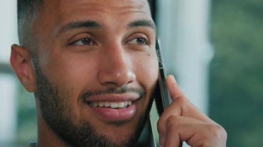 Gülümseyen Afro-Amerikalı, kıpır kıpır, mutlu iş adamı cep telefonuyla konuşan, sanal konuşma, uzaktan sipariş teslimatı, uzaktan arama görüşmeleri, arkadaşlarla görüşmeler.