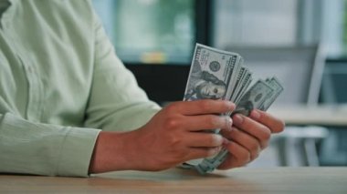 Yakındaki erkek, nakit paraları sayıyor. Kapalı alanda tanınmayan Afro-Amerikalı bir adam. Elinde dolar destesi tutan iş adamı.