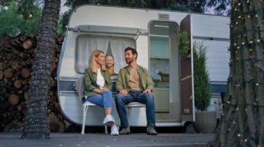 Evli çift, karı-koca, kamp alanında karavanın yanında oturan beyaz bir aile. Karavanda küçük bir kız çocuğunun penceresini açıp anne-babaya sarılıp tatile çıkması hakkında konuşuyorlar.