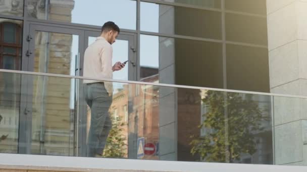 スローモーション高価な思いやりのあるビジネスマン大人の上司のリーダーの所有者のCeoは 現代的な会社のオフィスのバルコニーテラスを歩いて同僚のメッセージをオンラインで携帯電話のテキストメッセージとチャット — ストック動画