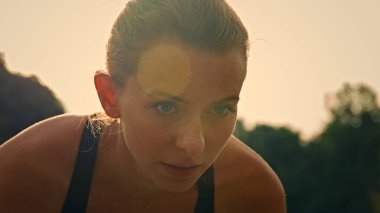 Motive olmuş genç kadın koşucu beyaz kadın koşucu başlangıç çizgisinde eğik pozisyonda oturur yarış maratonunu koşuya hazırlar koşuya hazırlanır gün doğumunda dışarıda spor antrenmanı hızı yapar