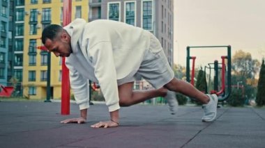 Sağlıklı Latin Amerikalı sporcu koşucu spor sahasında karın kasları için egzersiz yapıyor. Vücut geliştirme sporcusu karın ve kalça kaslarını çalıştırıyor.