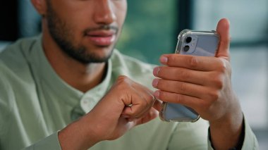 Yarım suratlı Afro-Amerikan sakallı adam kapalı bir yerde elinde akıllı telefon olan erkek müşteri işadamı cep telefonuyla ana ofiste oturup mobil uygulama kullanarak ekranda arama yapıyor.