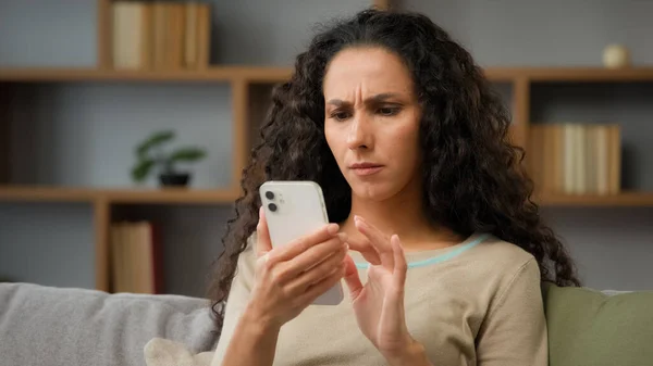Closeup angry confused puzzled stressed nervous adult woman looking at cellphone screen at home has trouble with wifi connection feeling frustrated of receiving message or email with bad news chatting