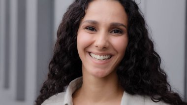 Yakın plan portre kadın mutlu turist iş kadını model 30 'lu yaşlarda Latin Latin beyaz kadın şehirde poz veriyor kameraya bakan dişlek gülüşüne bakıyor.