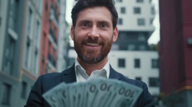 Zengin ve başarılı iş adamının elinde gelir maaşı dolarları var. Zengin kazanç ödülü var. Banknotların çoğu kârlı iş anlaşmasının tadını çıkarıyor.