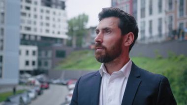 İlham verici iş adamı sakallı beyaz adam başarılı işçi şehir merkezindeki caddeye bakıyor profesyonel hedefleri düşünüyor kariyer planları yapıyor derin düşüncelere dalıyor.