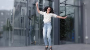 Funny crazy laughing active woman success lucky dancer tourist lady jump high in air near city building outdoors on street having fun jumping flying moving celebrate vacation holiday looking at camera