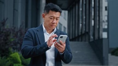 Şehirdeki Asyalı iş adamının cep telefonuyla ilgili sorunları var. Orta yaşlı CEO işveren dışarıda gezen bir girişimci bozuk bir hataya üzülüyor çevrimiçi cep telefonu bağlantısını kaybediyor