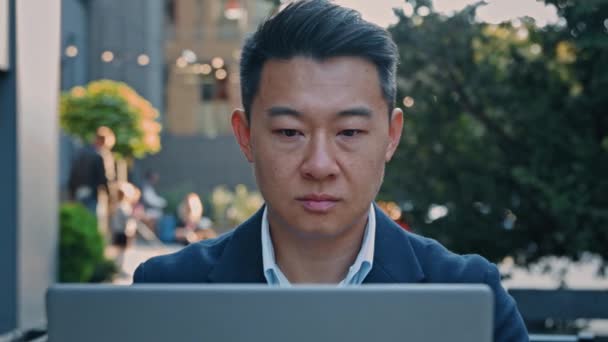 严重的亚洲中年商人经理雇主男子在室外工作时与笔记本电脑一起打字 城市外的电脑聊天行业在线电子商务远程工作互联网工作Wi Fi连接 — 图库视频影像