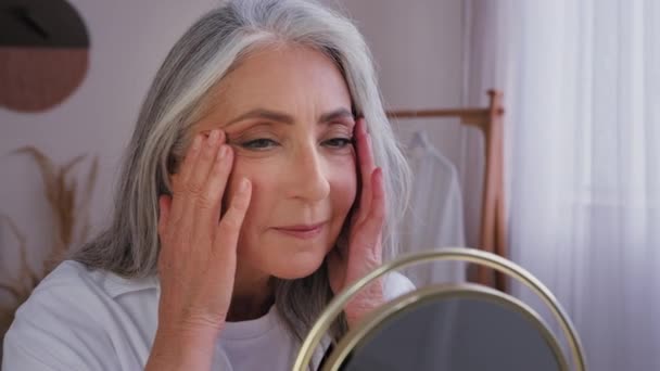 六十多岁的白发老年妇女 五十多岁的老太太 满脸皱纹 美丽衰老的脸 完美光滑的皮肤 镜像反射 触摸面颊按摩护肤美容术 — 图库视频影像