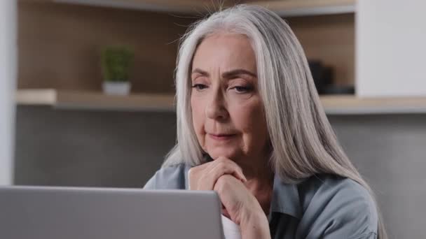 年长的退休妇女把下巴放在折叠的手掌上 心烦意乱的老妇人坐在家里 用无线网络连接现代互联网技术与家人进行在线视频聊天 观看屏幕笔记本电脑 — 图库视频影像
