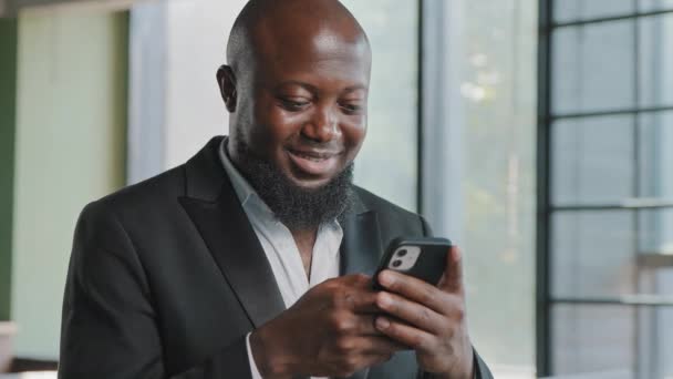 男性の大人のビジネスマンの投資家は オフィスでオンライン近代的な技術を購入する電子商取引のためのモバイルビジネスアプリを使用して電話でメモを取るソーシャルネットワークでスマートフォンのテキストメッセージを保持男 — ストック動画