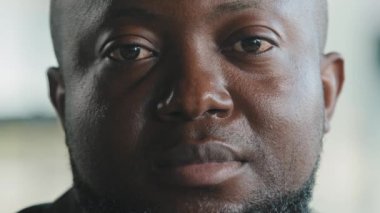 Hüsrana uğramış Afrikalı yetişkin bir adam ve büyük, yalnız bir adam. Kameraya bakıyor. Dalgın, umutsuz bir manzara.