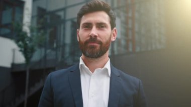 Şık başarılı Kafkasyalı iş adamı resmi takım elbise giyiyor mutlu erkek portresi yetişkin 30 'lu yaşlarda sakallı, orta doğulu çekici bir adam güneşli bir günde modern şehir merkezinde poz veriyor.