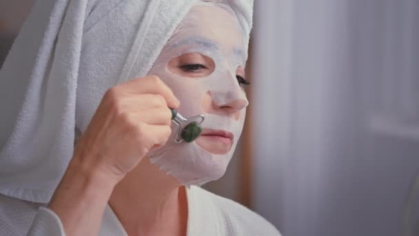 白种人老太太老年老太太在浴室里 头戴毛巾 头戴石粉面罩 做面部按摩 用石粉和纺织品面罩护理皱纹肌肤美感肌肤更新疗法 — 图库视频影像