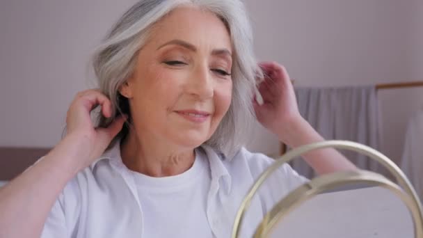閉店60歳中年笑顔幸せなスタイリッシュな健康的な成熟した白人女性祖母50代女性ミラー反射を見ます白髪に触れ幸せなヘアケア手順シャンプー — ストック動画