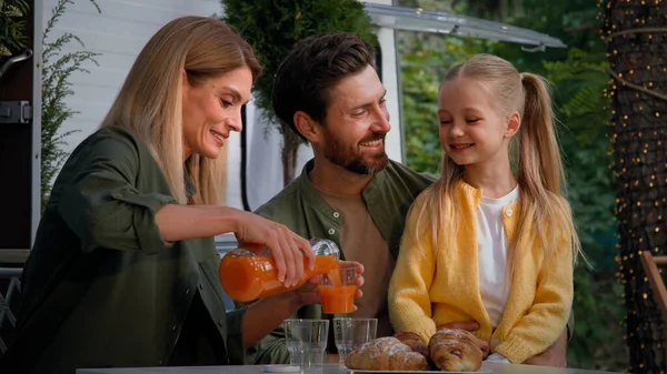 白种人家庭在户外露营度假时坐在面包车旁吃午饭野餐 和牛角面包妈妈一起吃得很好 把新鲜的橙汁倒入玻璃杯给父亲和孩子的小女儿 — 图库照片