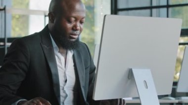 Orta yaşlı profesyonel yönetici Afrikalı yetişkin adam bilgisayar ticareti üzerinde çalışıyor çevrimiçi internet üzerinden web sitesi programlama verileri geliştirerek internet e-postalarında kameraya gülümsüyor