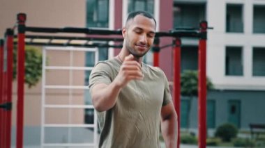 Yakışıklı Latin sporcu atletik sporcu spor eğitmeni hoş geldin jesti yapıyor aktif sağlıklı yaşam tarzı sağlık motivasyonunun şehir spor sahalarındaki eğitime katılması için takım reklamına davet ediliyor.