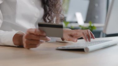 Kredi kartı tutan tanınmayan bir kadın, klavye işadamının bilgisayarındaki veriye giriyor ve güvenli ödemeler için bankacılık başvurusunu kullanarak online mağazada ödeme yapıyor.