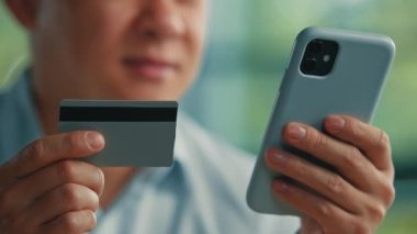 Erkek müşteri yetişkin Asyalı Japon işadamı mobil bankacılık uygulaması ile online ödeme yapıyor elektronik para transferi için kredi kartı kullanıyor güvenli ödemeler modern teknoloji uzaktan kolayca satın alınıyor