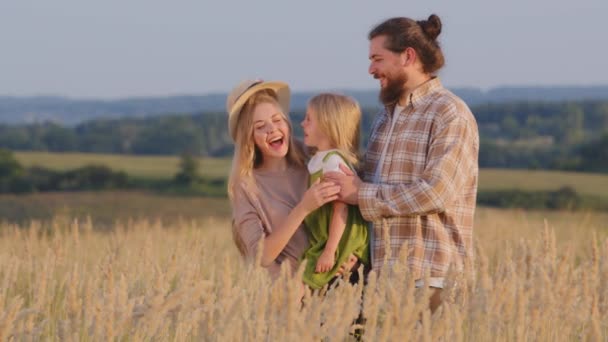 白种人家庭站在麦田的室外 母亲抱着女儿 父亲摘下妻子的草帽 头上挂着孩子 笑着可爱地粘合在一起 — 图库视频影像